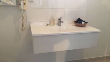 Un baño con un lavabo blanco, un secador de pelo y una caja de pañuelos en la pared.