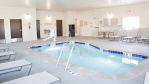 A swimming pool with a no diving sign, lounge chairs, and exit signs.