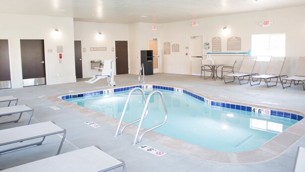 A swimming pool with a no diving sign, lounge chairs, and exit signs. - Microtel Inn & Suites by Wyndham Springville/Provo (Springville)