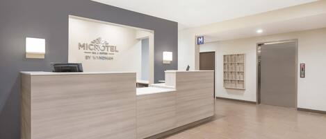 Una reception con un cartello che riporta le scritte 'MICROTEL' e 'WANDHAIM' in un moderno atrio di hotel.