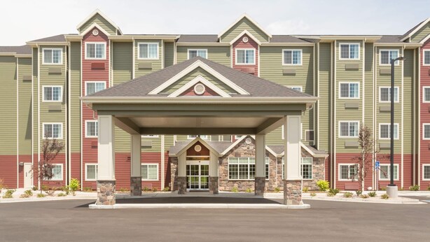 A multi-story hotel with a covered entrance, stone pillars, and a red door.