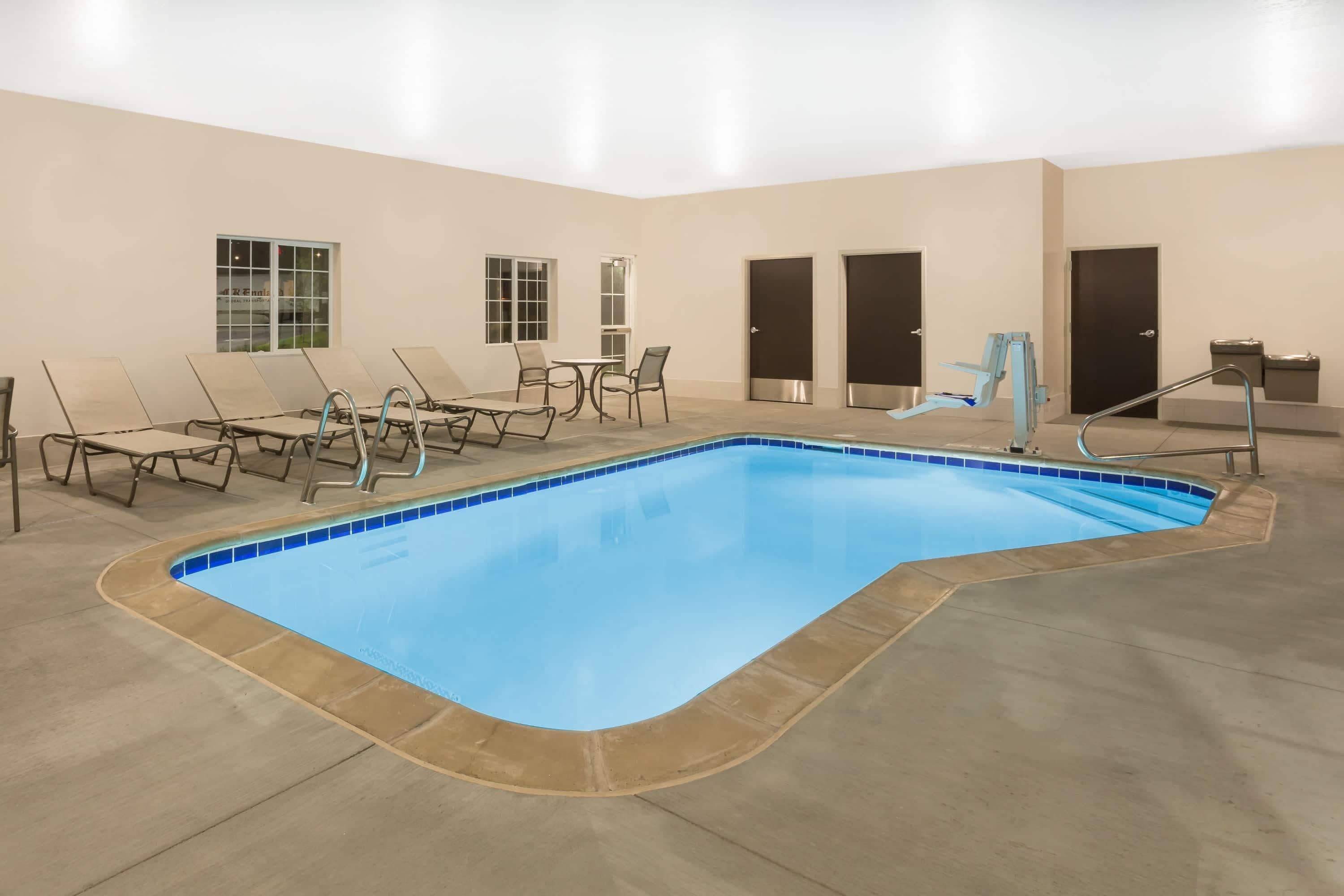 Une piscine intérieure dotée de chaises longues et de portes.