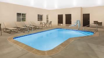 Piscina interna com espreguiçadeiras e portas.