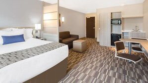 A hotel room with a bed, a desk, a chair, a sofa, a microwave, and a small kitchenette. - Microtel Inn & Suites by Wyndham Springville/Provo (Springville)