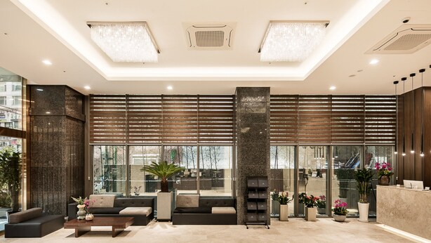 Una hall moderna con reception, area relax e ampie finestre.