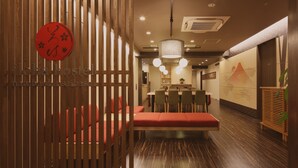 Un restaurante con separadores de madera, asientos rojos y una mesa central para comer.