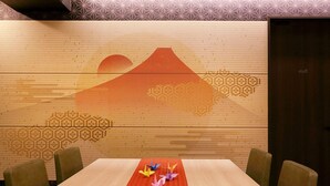 Un salón de conferencias con una mesa de madera, sillas y una pared con motivos de montañas y formas hexagonales.