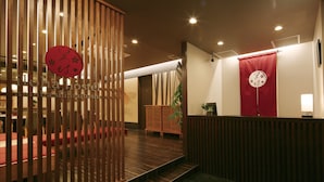 Un área de recepción con un mostrador de madera, una cortina roja y un reloj en la pared.