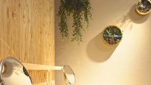 Un mur en bois orné d’un miroir rond et de deux plantes en pot.