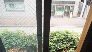 A window with a view of a building and a potted plant outside. - North Front Hostel (Fukuchiyama)
