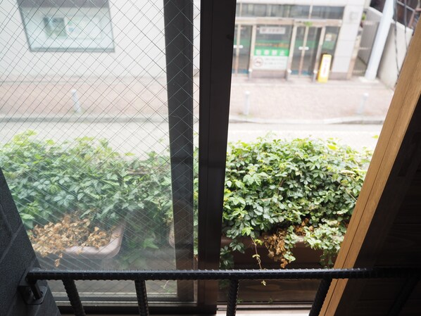 Una ventana con vista a un edificio y una planta en maceta afuera.
