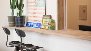 A reception desk with a wooden top, two black chairs, a cactus plant, a California sign, and a framed quote. - North Front Hostel (Fukuchiyama)
