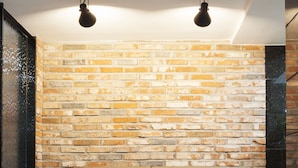 A modern living room with a brick wall, leather sofa, and a glass coffee table. - Hotel Leaders (Seoul)