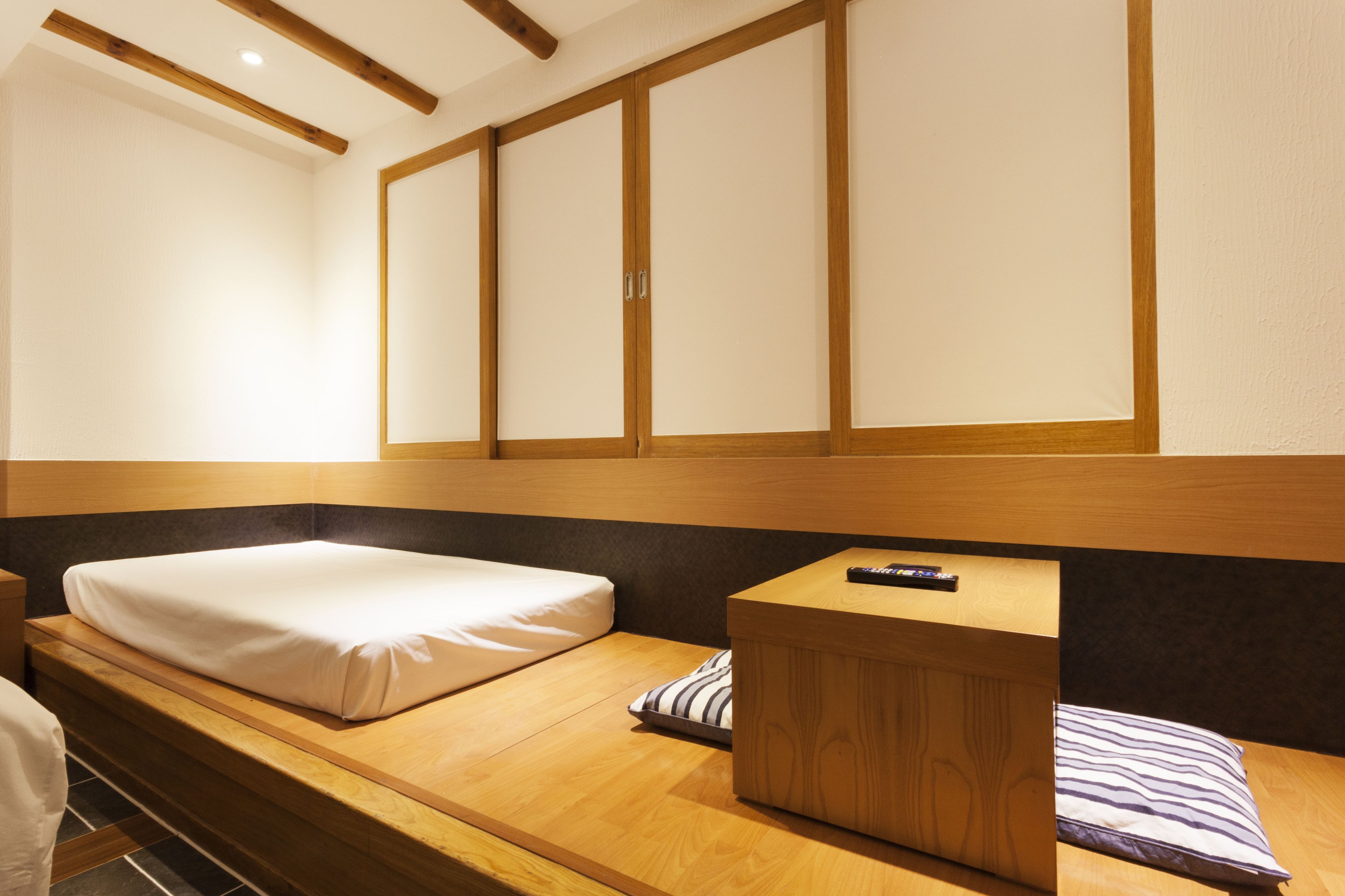 A single bed with a wooden headboard, a bedside table, and a pillow.