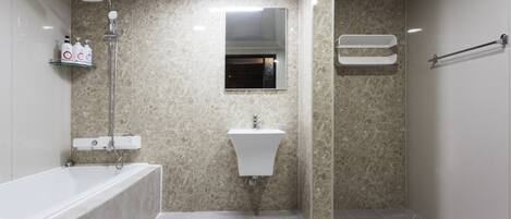 Een moderne badkamer met een bad, een wastafel, een douchekop en een spiegel.