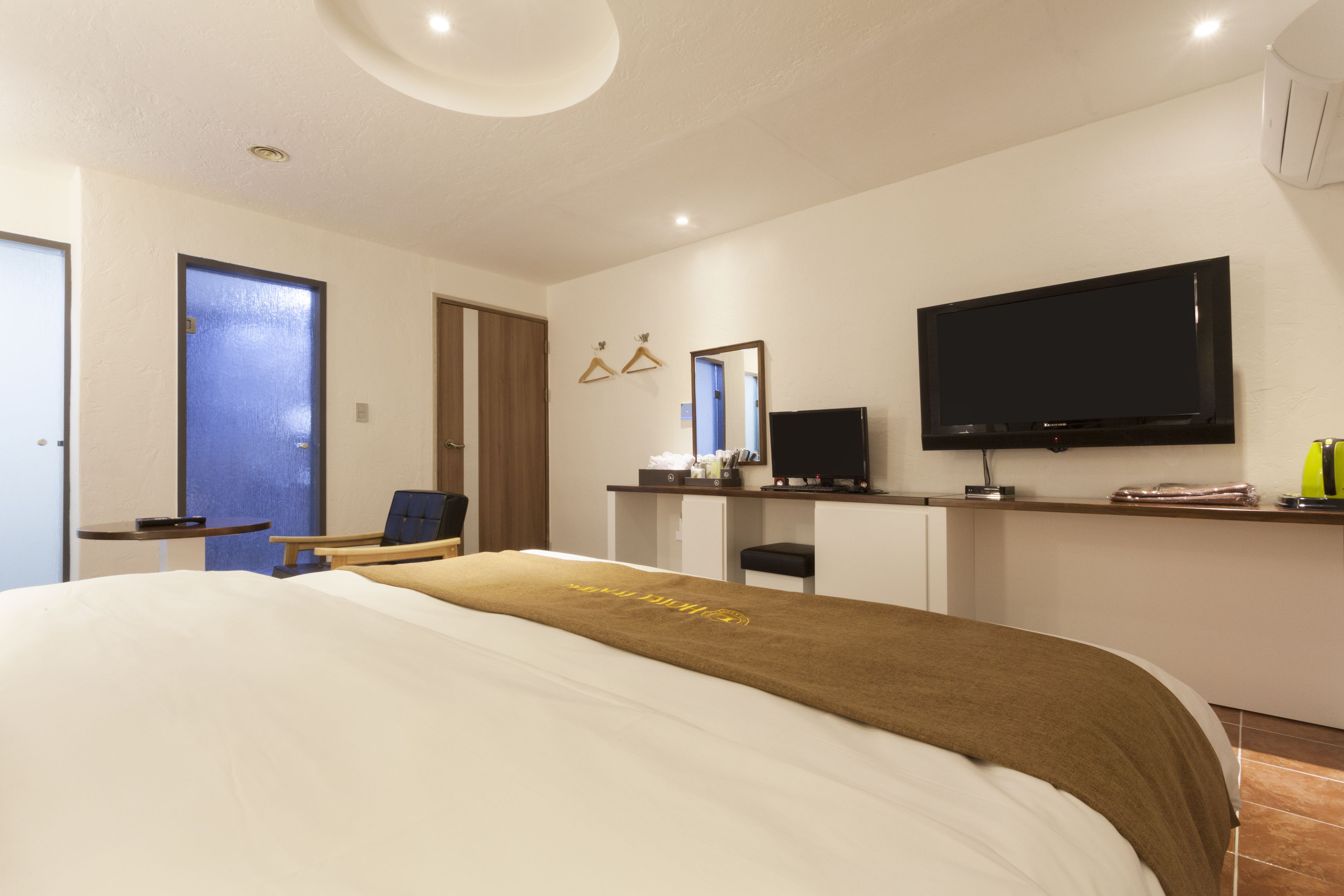 Una habitación de hotel moderna con una cama grande, un escritorio, un televisor y un espejo.
