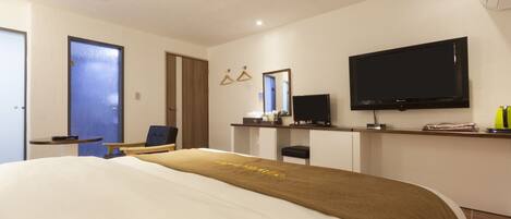Una habitación de hotel moderna con una cama grande, un escritorio, un televisor y un espejo.