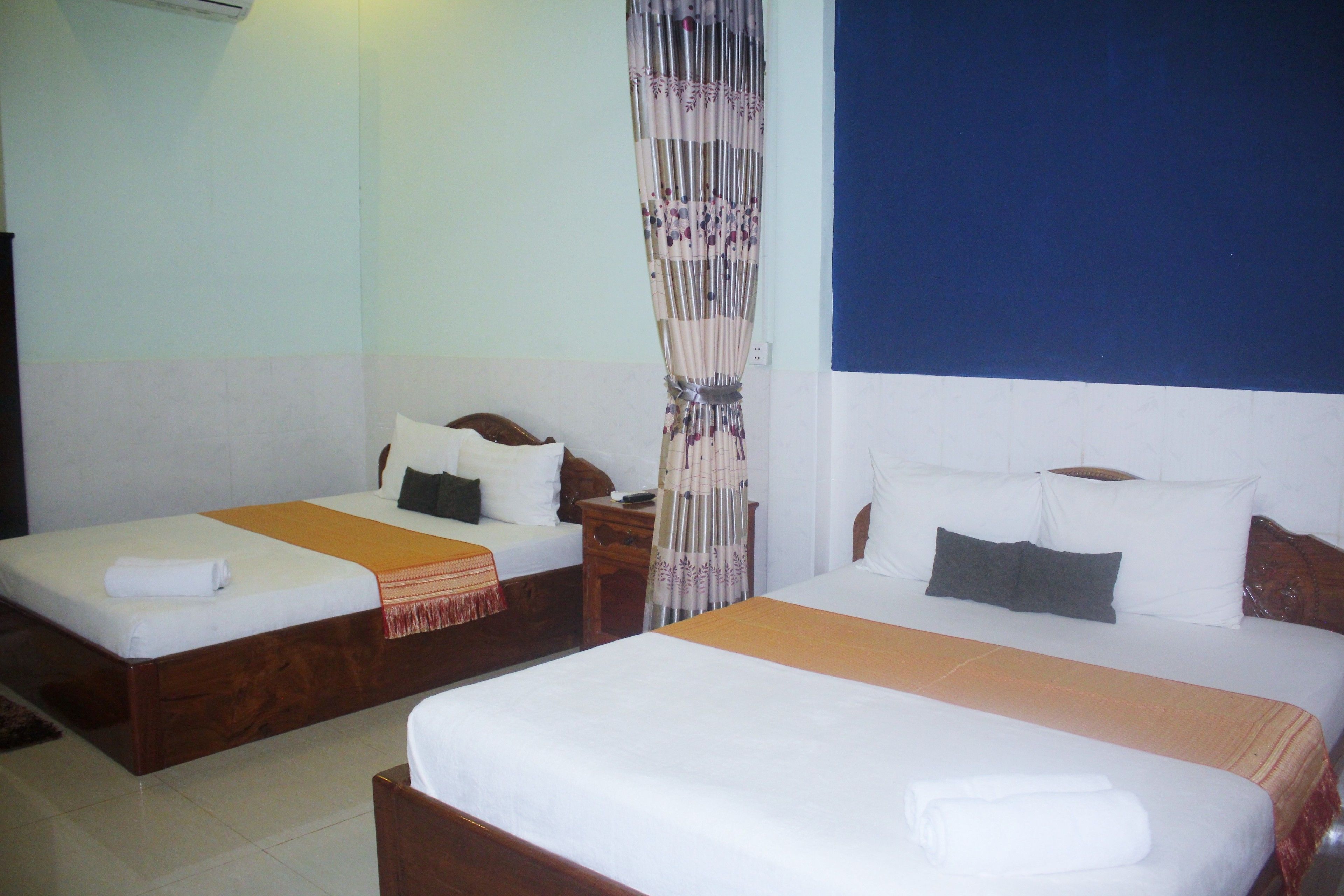 Two single beds with wooden frames, white bedding, and orange throw blankets.