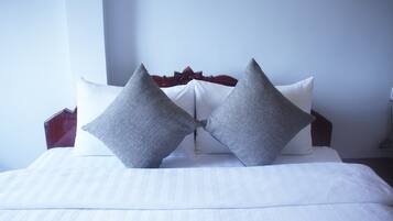 A neatly made bed with white linens and two gray pillows.
