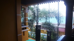 A pool area with palm trees and a view of a building with a yellow facade. - Ramchang Guesthouse (Battambang)