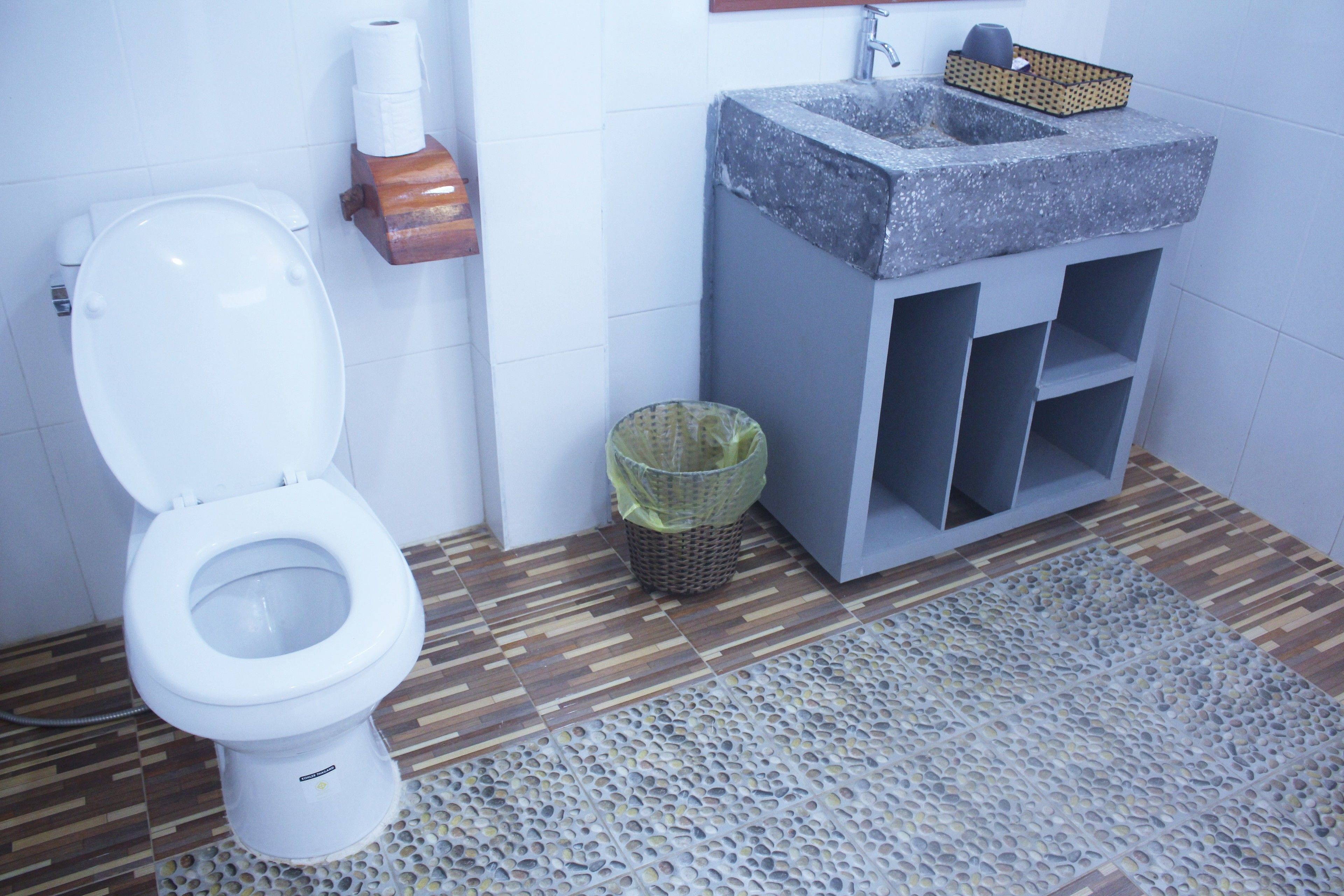 A bathroom with a toilet, a sink, and a waste basket.