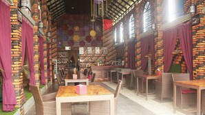 An indoor restaurant with brick walls, wooden tables, wicker chairs, and a bar area. - Ramchang Guesthouse (Battambang)