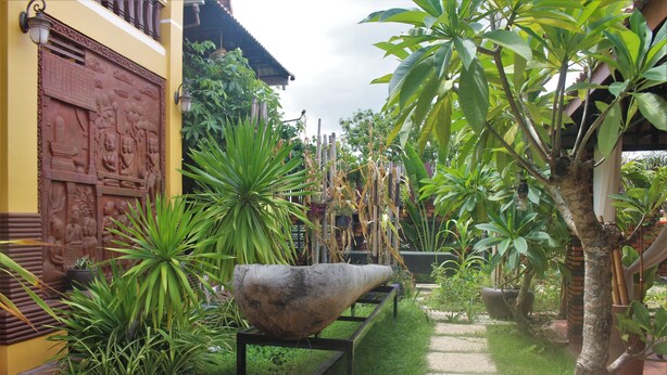 A courtyard with a large stone basin, potted plants, and a decorative wall. - Ramchang Guesthouse (Battambang)