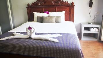 Una cama bien hecha con una colcha azul estampada y dos toallas con forma de cisne.
