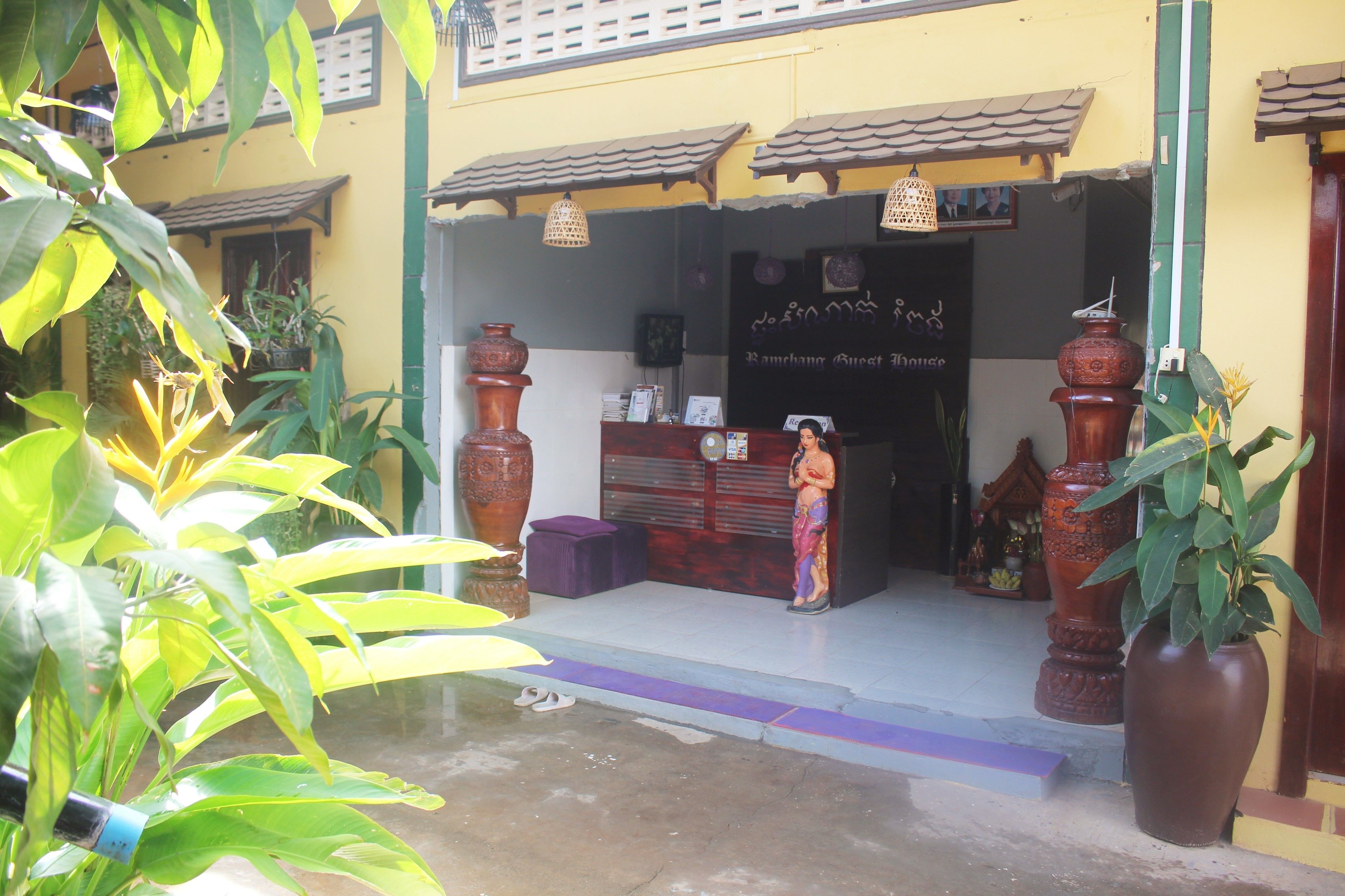 A building entrance with a reception desk, large decorative vases, and potted plants.
