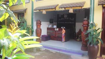 A building entrance with a reception desk, large decorative vases, and potted plants.