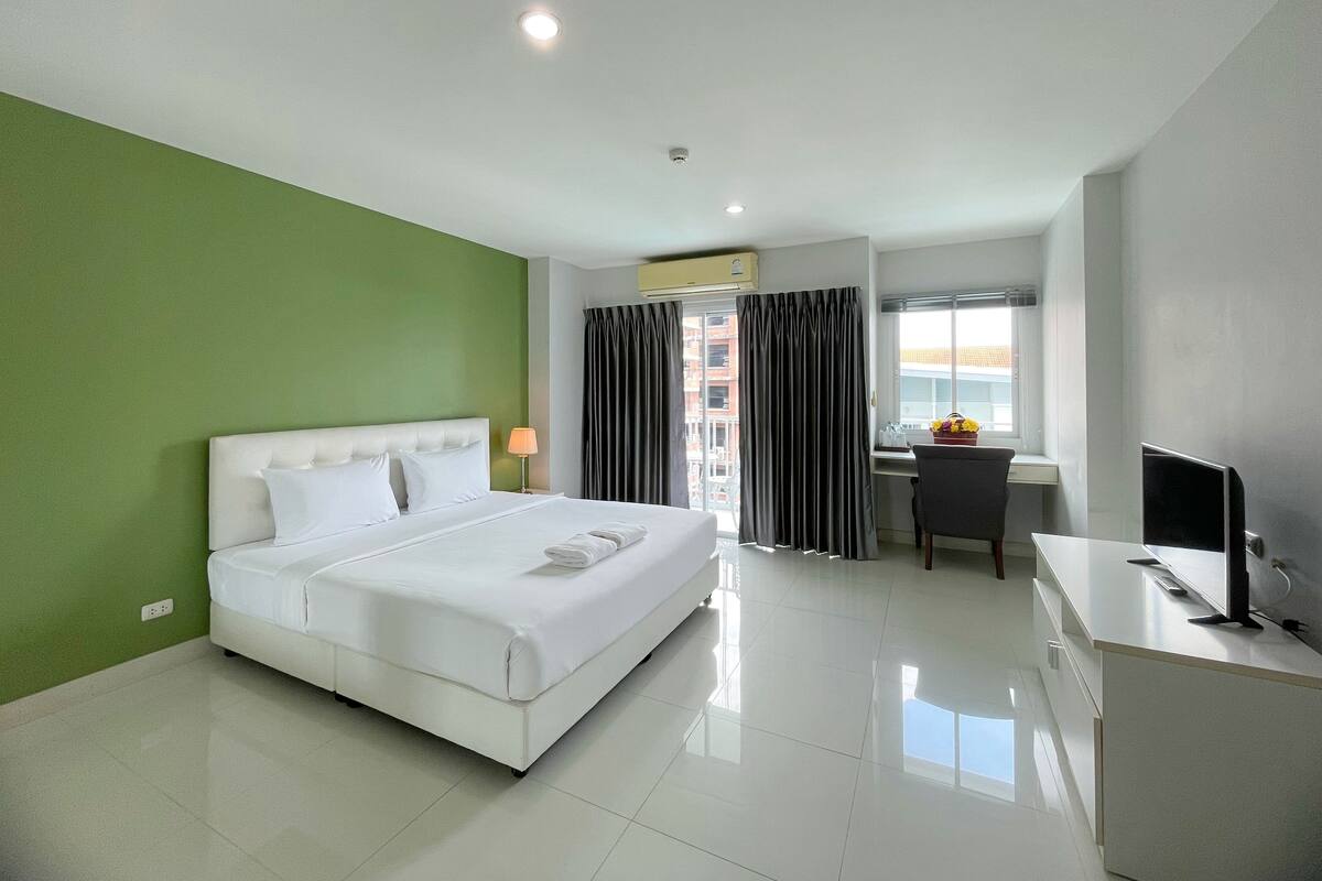 A hotel room with a bed, a desk, a chair, and a TV.