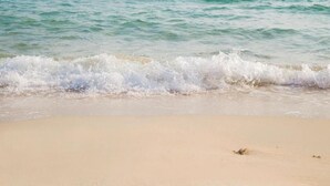 A beach with waves gently lapping onto the shore. - Baan Pattaya by Sabai (Pattaya)