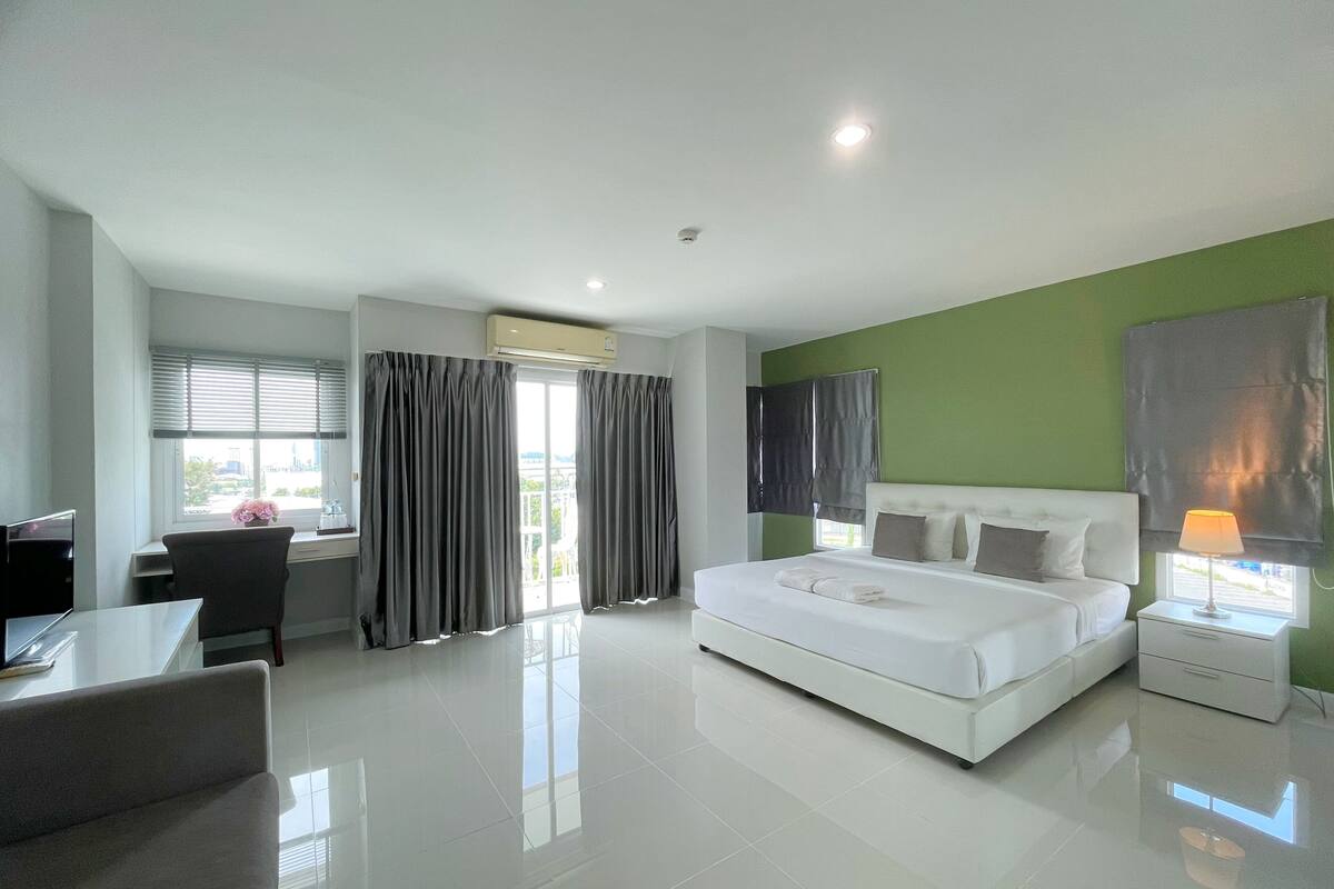 A modern hotel room with a large bed, a desk, and a chair.