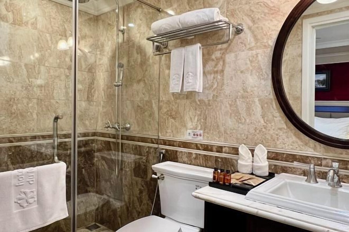 Une salle de bain avec une douche à parois de verre, des toilettes blanches et un lavabo équipé de produits de toilette.