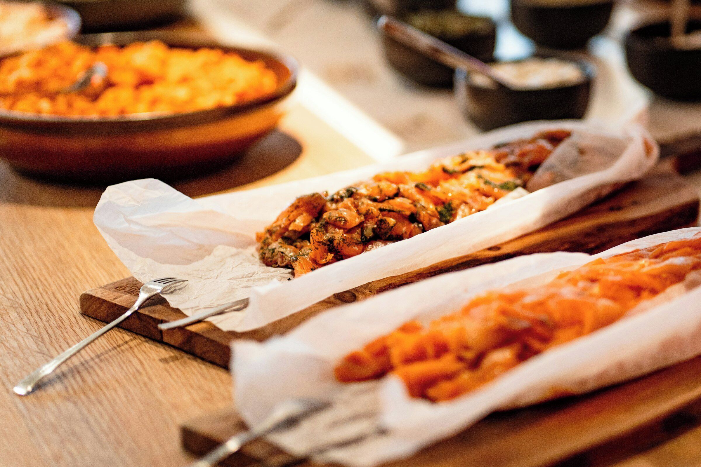 A wooden table with food items, a fork, and a spoon.