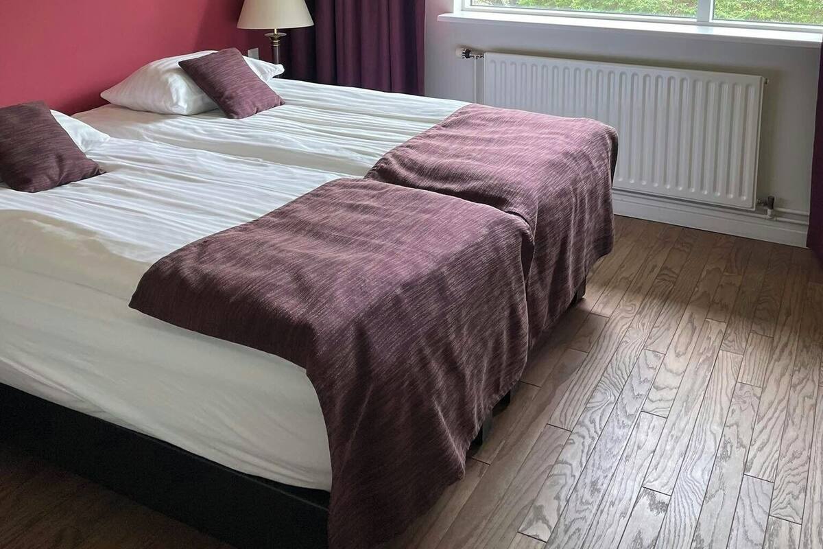 Ein Hotelzimmer mit Bett, Fenster, Heizkörper und Lampe.