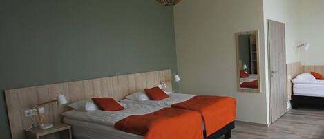 A hotel room with a bed, bedside table, lamp, and a mirror.