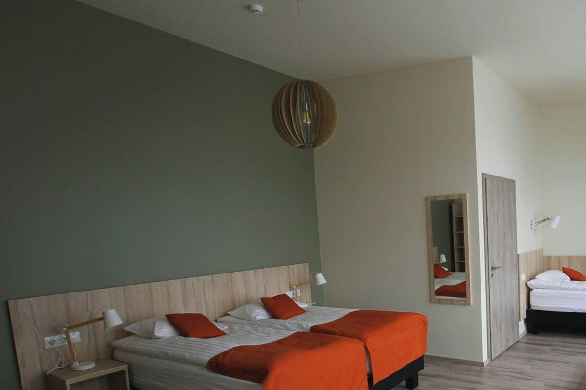 A hotel room with a bed, bedside table, lamp, and a mirror.