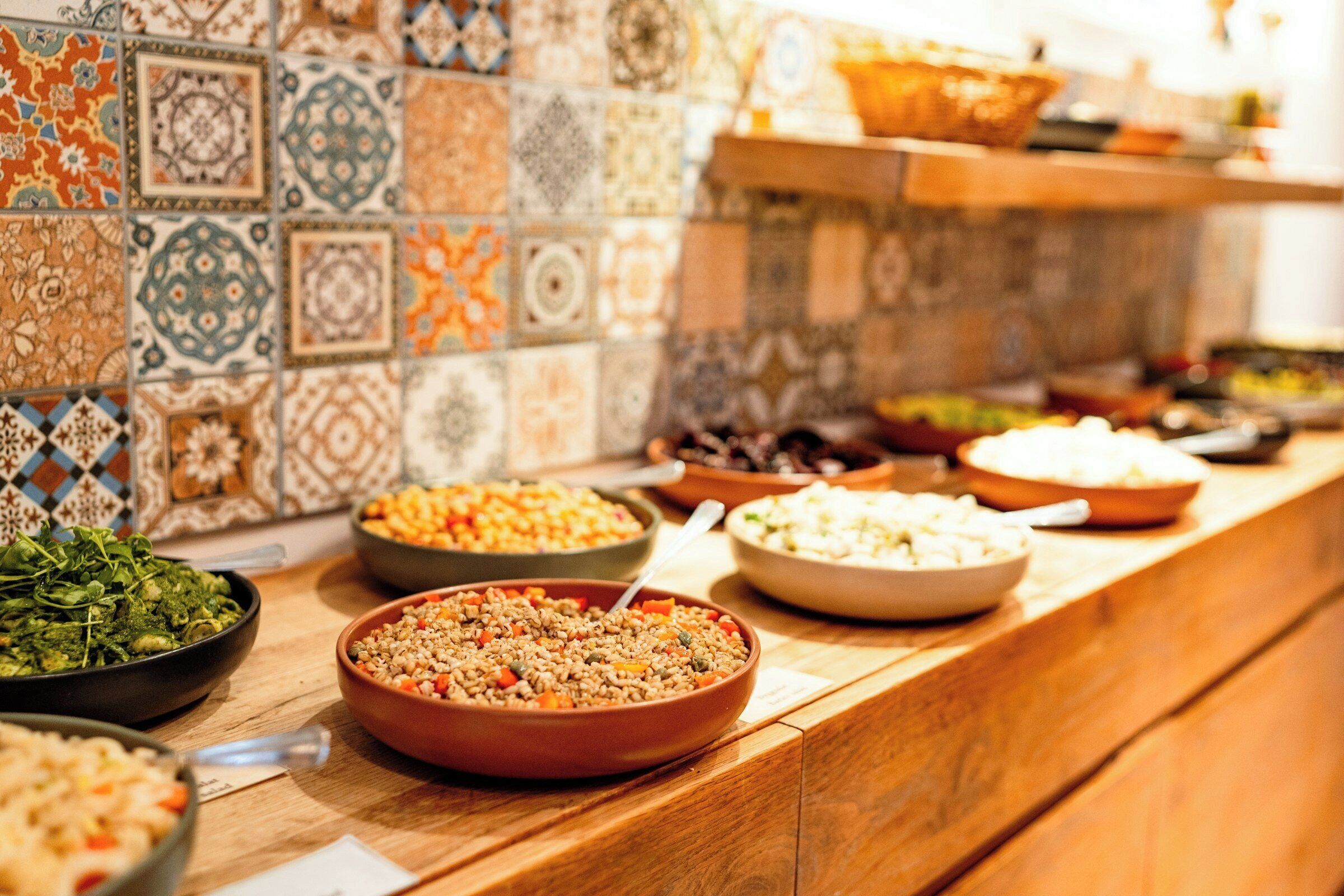 Un bufé con diversos platos, una pared de azulejos y una encimera de madera.