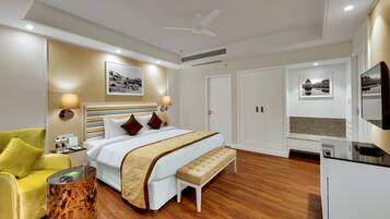 Una habitación de hotel moderna con una cama grande, un sillón amarillo, una mesita de noche y un espejo.