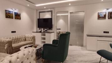 Una sala de estar moderna con un sofá, sillones, una mesa de centro y un televisor de pantalla plana montado en la pared.