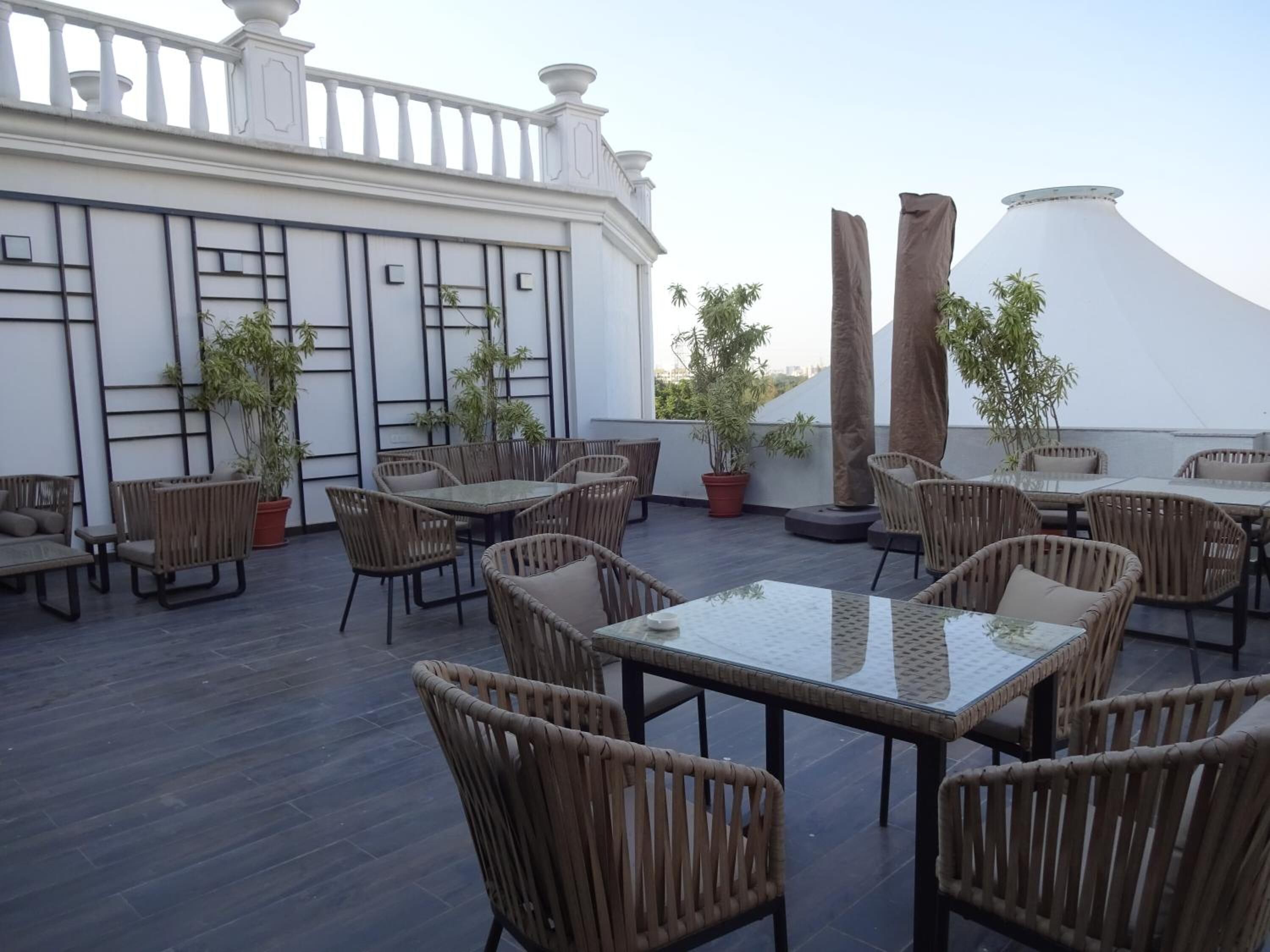 Un patio exterior con mobiliario de mimbre y plantas en macetas.