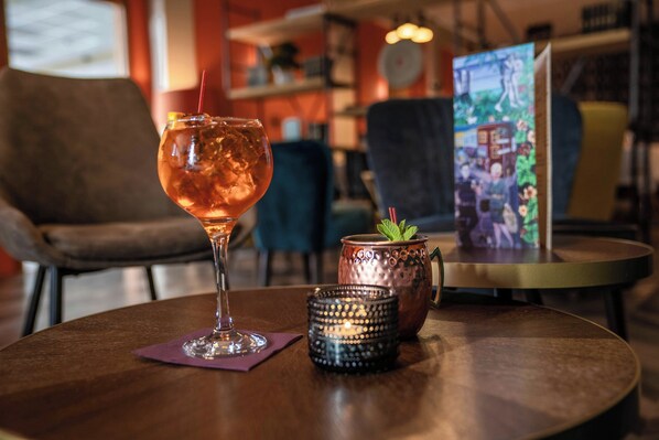 A bar setting with a cocktail glass, a copper mug, and a candle on a round table. - Hótel Valaskjálf (Egilsstaðir)
