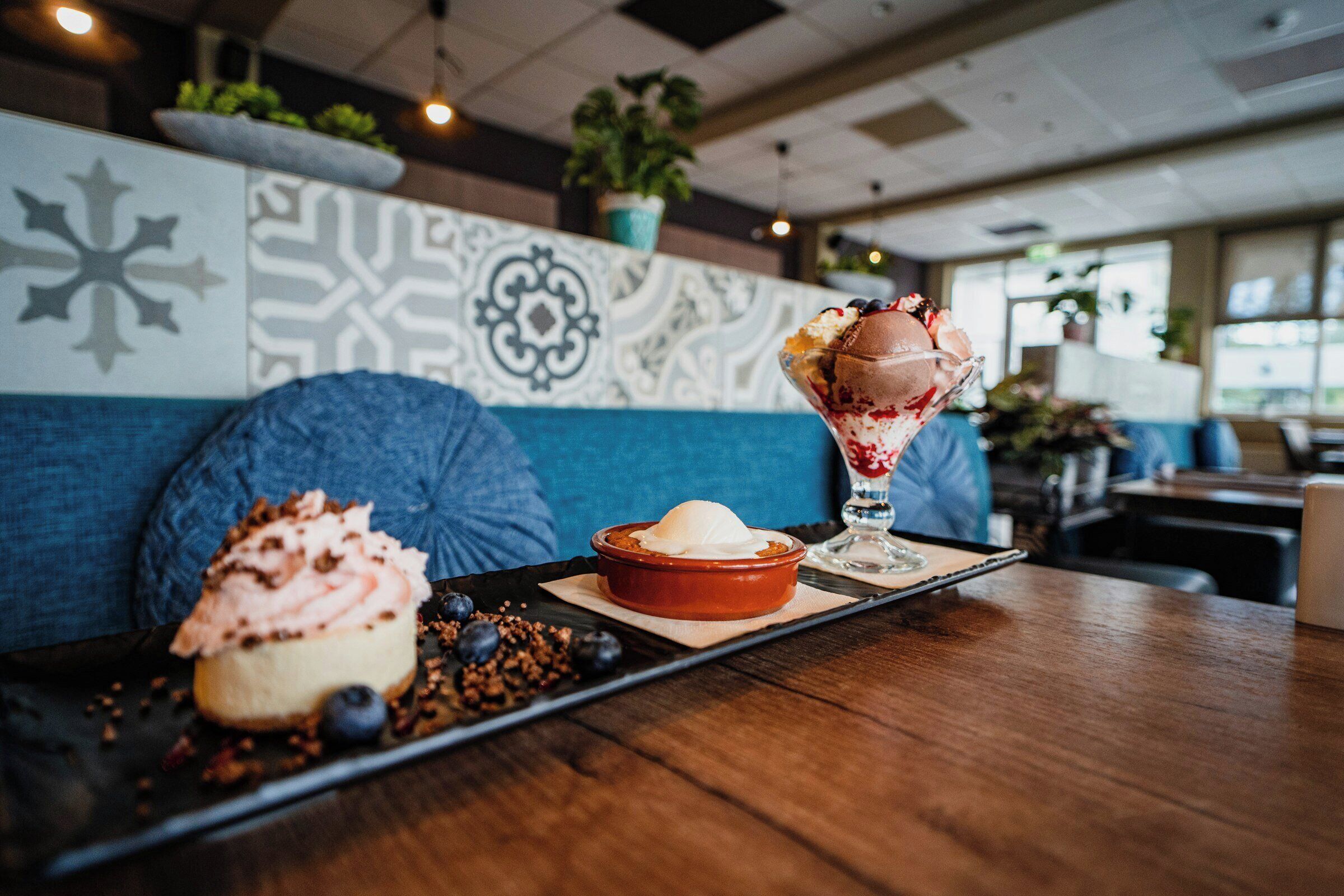 A dessert tray with a cupcake and a sundae on a wooden table in a restaurant.
