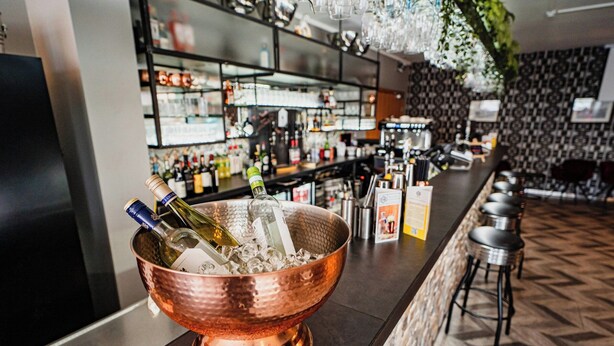 Una zona de bar con un bol de cobre lleno de botellas, una barra y un suelo estampado.