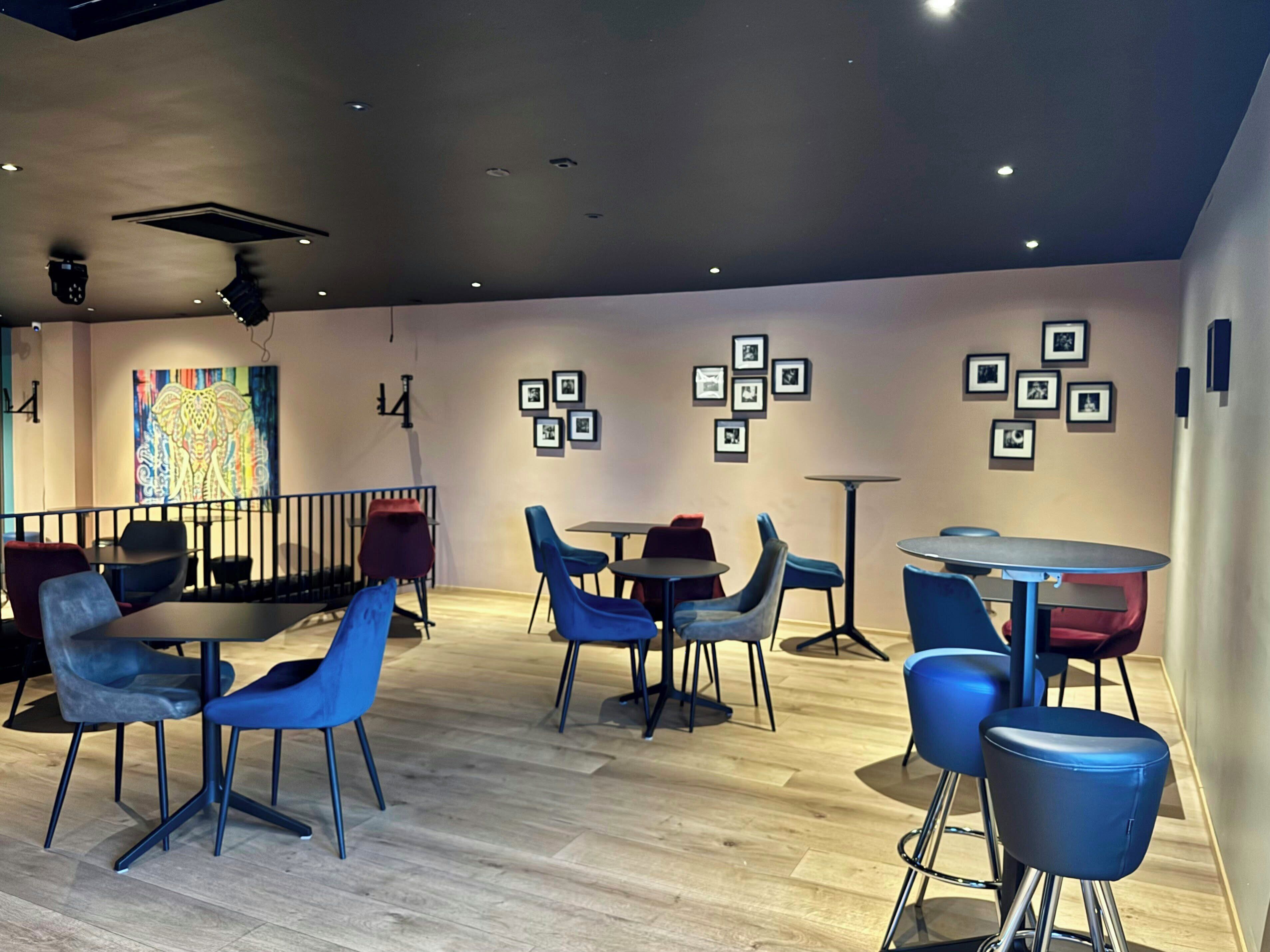 A modern interior with a mix of seating options, including tables and chairs, and a decorative wall with framed pictures.