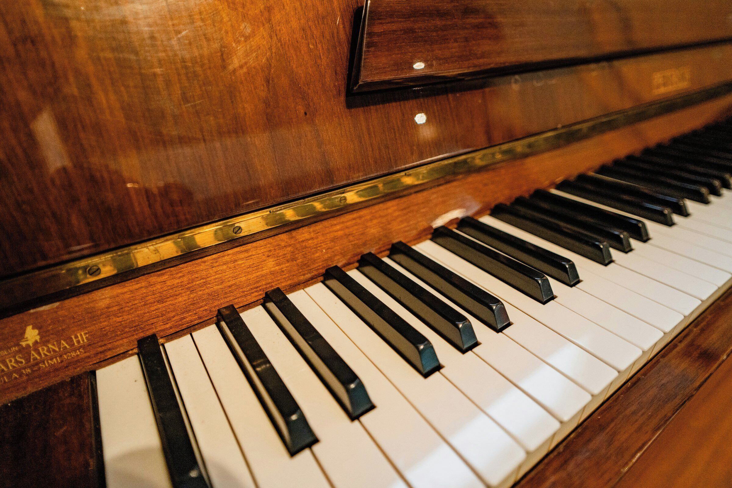 Primer plano de las teclas y el cuerpo de madera de un piano.
