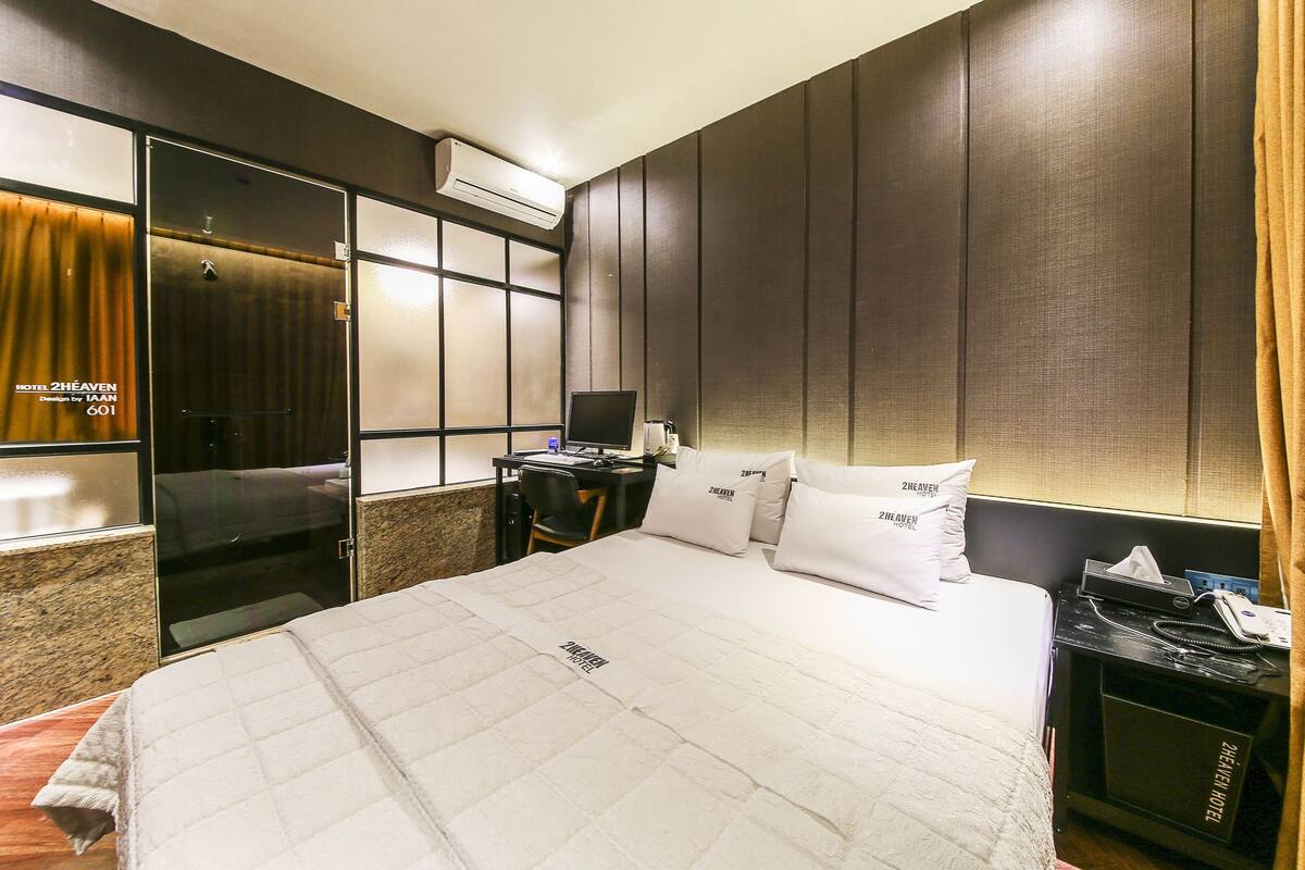 Et hotelværelse med seng, skrivebord med computer, telefon og minibar.
