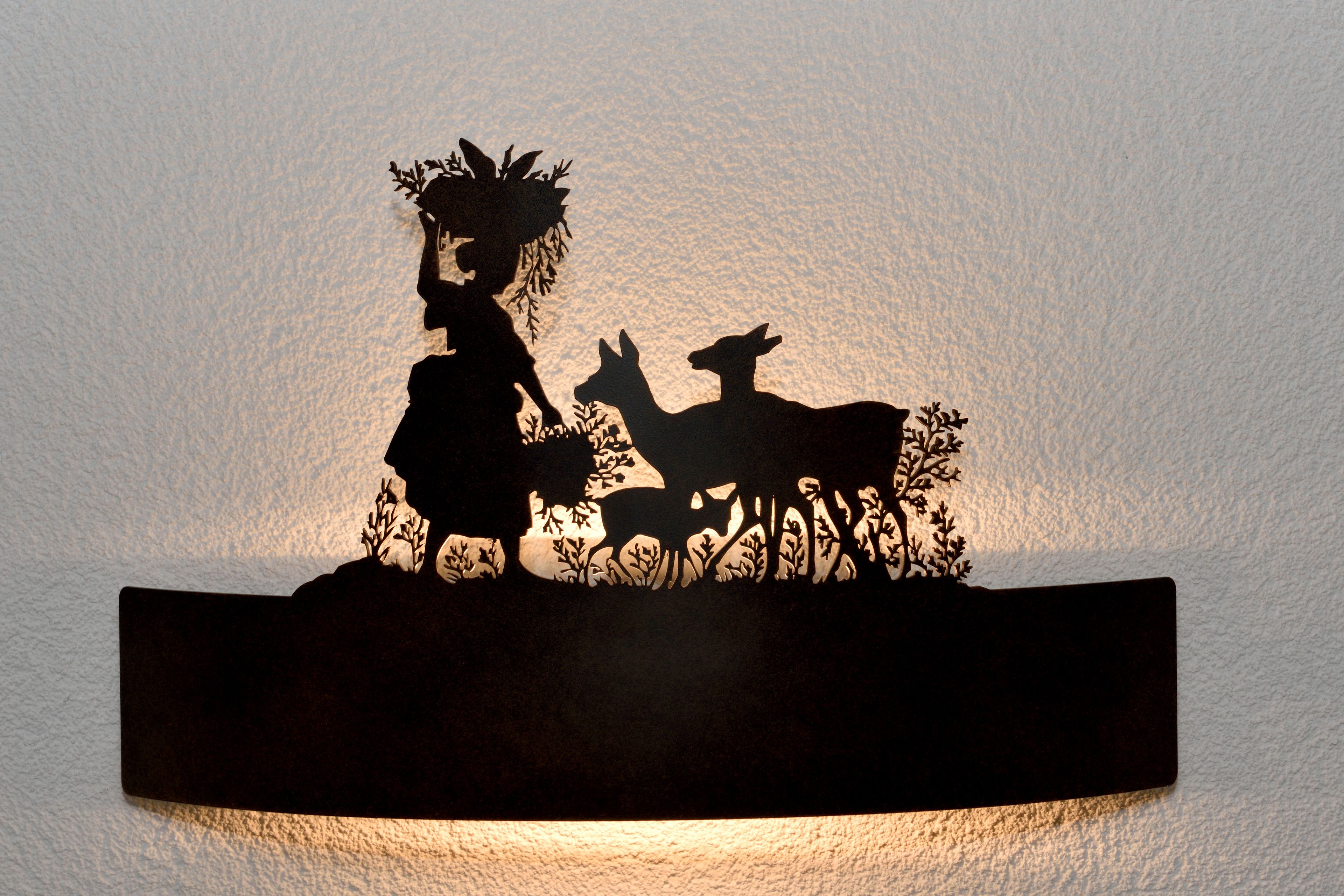 Silhouetten van een vrouw met een mand en een kind, en een hond op een muur.