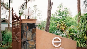 Paredede pedra com um portão de metal, um poste de luz e o logotipo de 'ecostudio Tellini'.